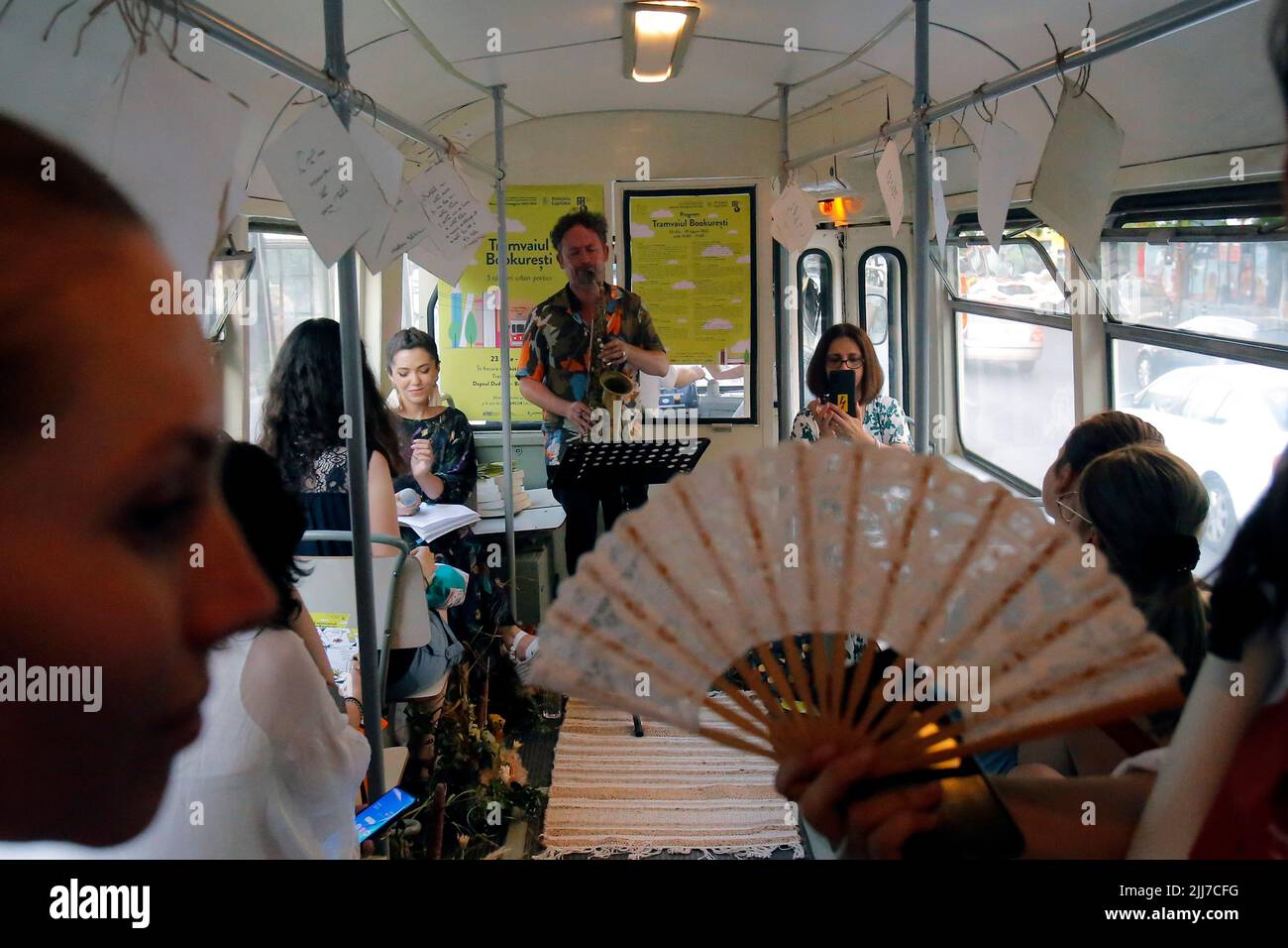 Bucharest, Romania. 23rd July, 2022. People attend a cultural event called 'Tramvaiul Bookuresti' (Bookarest Tramway) in a vintage tram in Bucharest, capital of Romania, July 23, 2022. Organized by the Cultural Centre of the Townhall, the cultural event is hosted in a vintage tramway where people could listen to poetry, music and historic stories about the town during a two-hour trip. Credit: Cristian Cristel/Xinhua/Alamy Live News Stock Photo