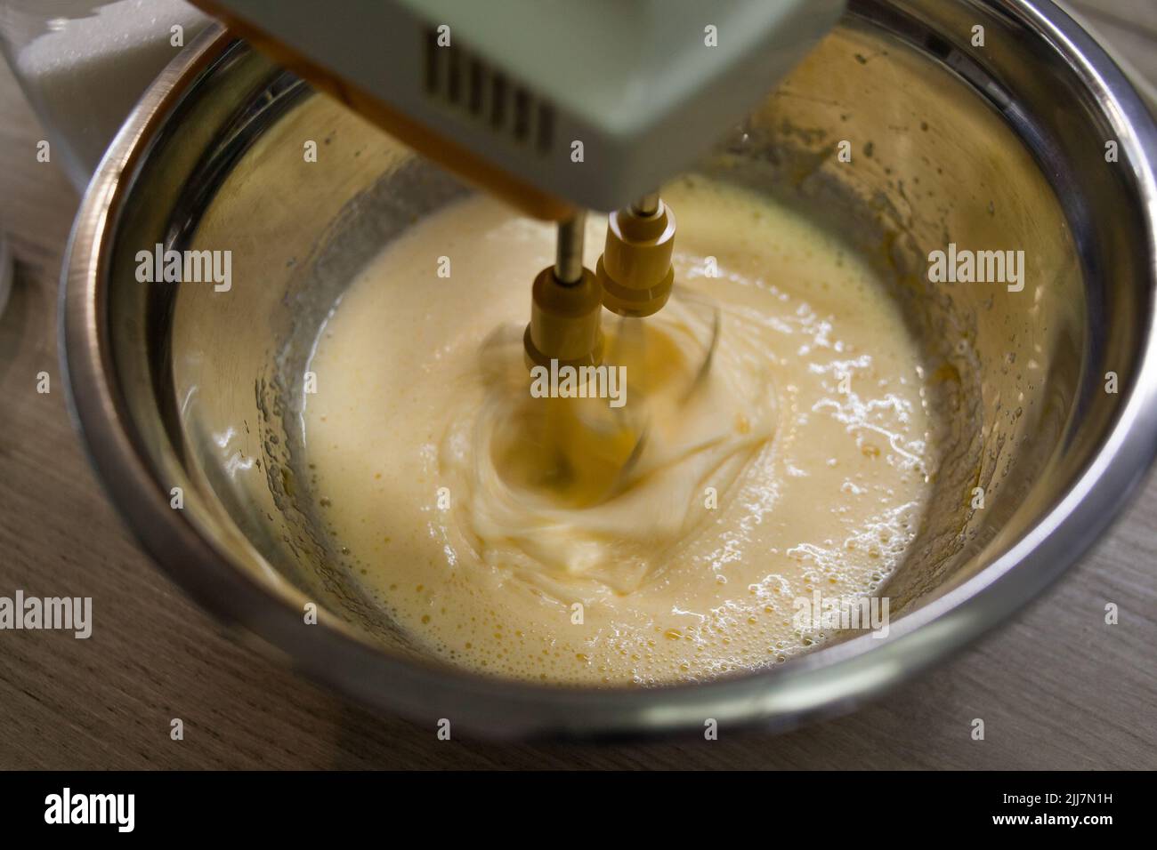 Beating with electric mixer sugar and eggs in a bowl Stock Photo
