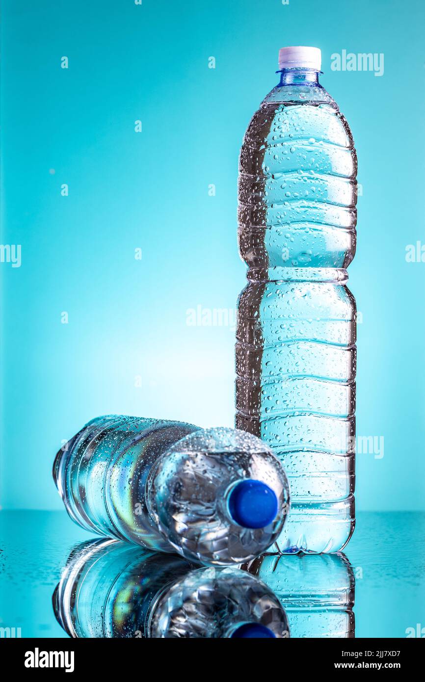 Two plastic cold bottles of water with water drops on a blue background. Stock Photo