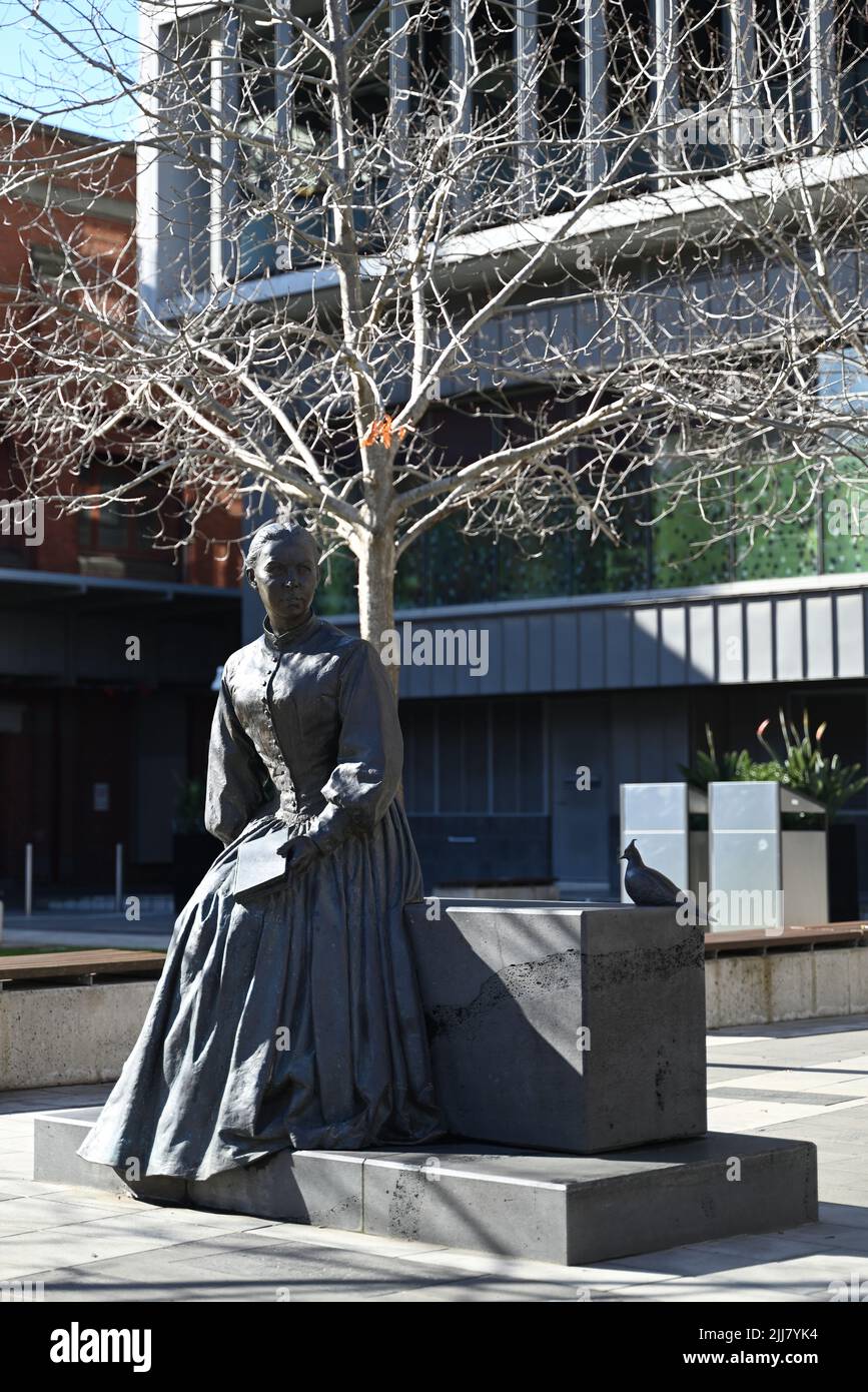 Sculpture of Catholic saint Mary MacKillop, sitting with book in hand next to a pigeon, outside ACU's Melbourne campus Stock Photo