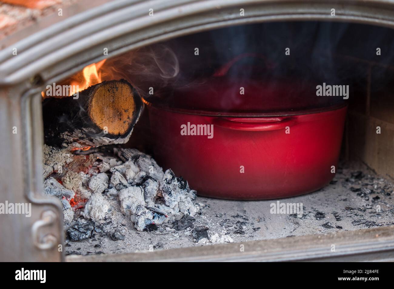 Cooking in stone oven. Cast iron pot in wood-fired oven. Stock Photo