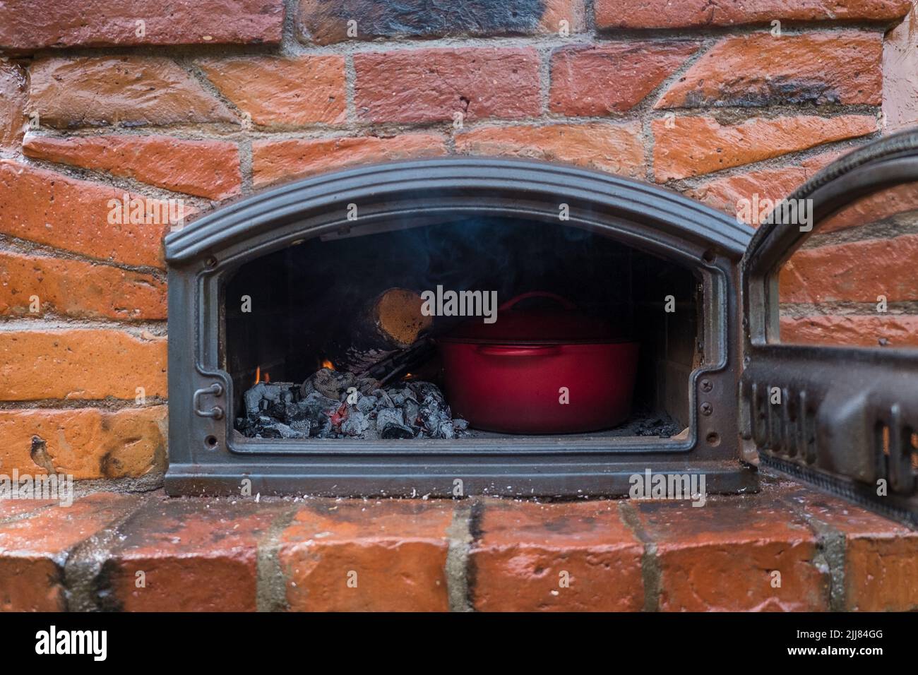 Cooking in stone oven. Cast iron pot in wood-fired oven. Stock Photo