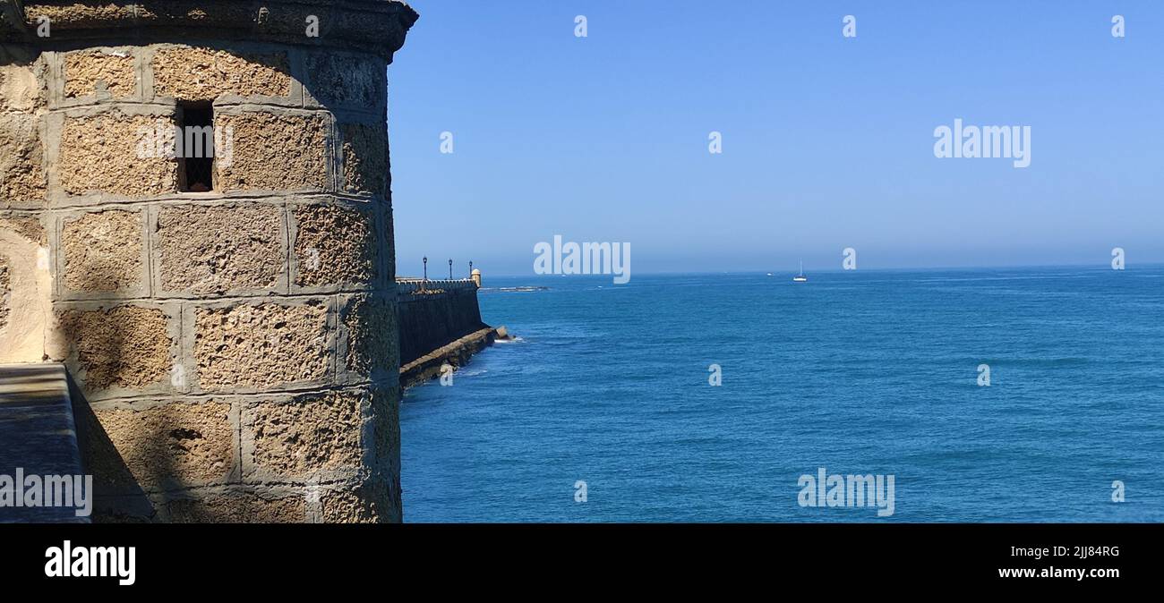 View of the sea and blue sky on the coast of Cadiz and a historic sentry box.  Stock Photo