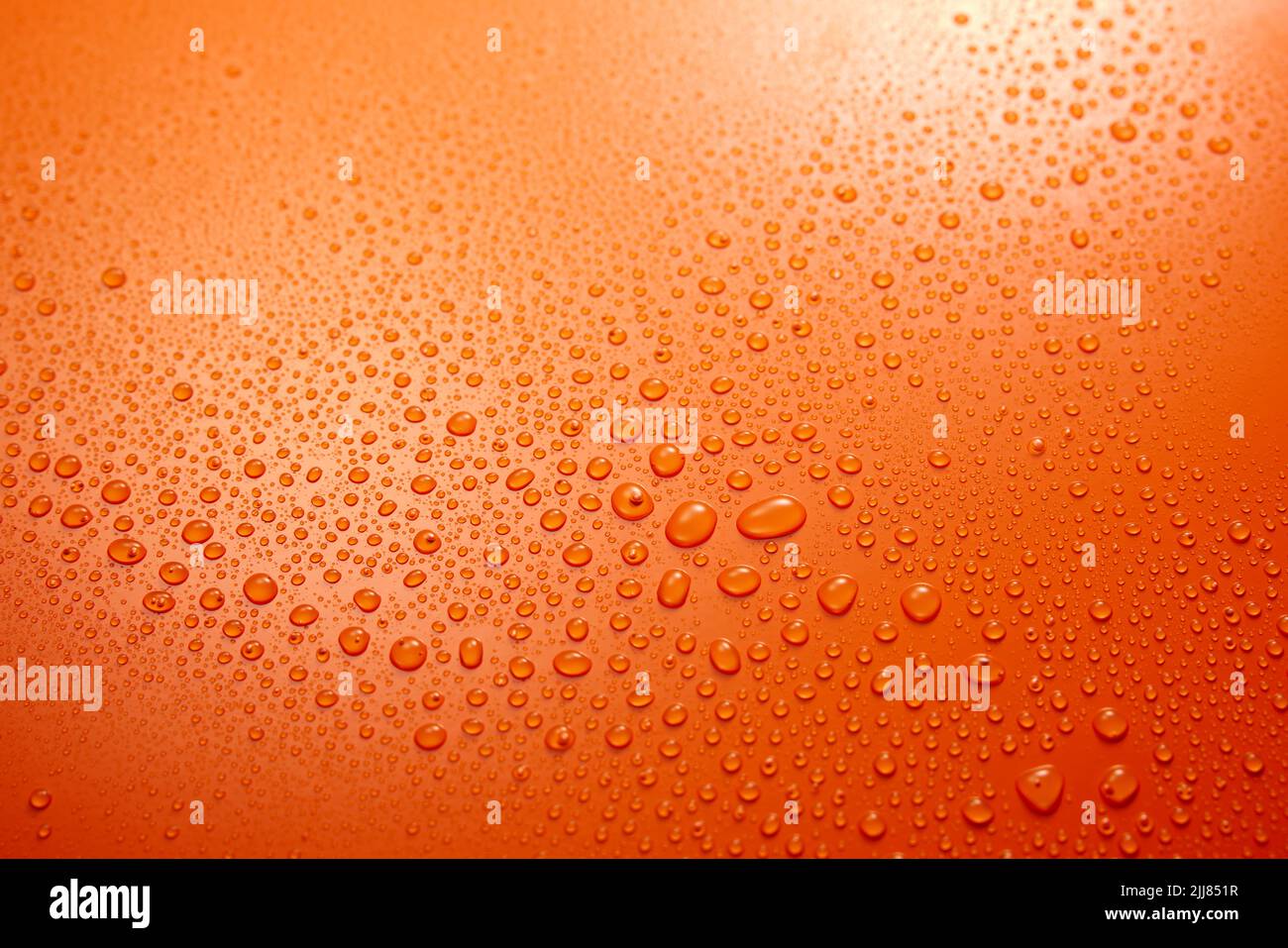 Full frame of wet clear orange background with condense and clear small round water drops flowing down in light room Stock Photo