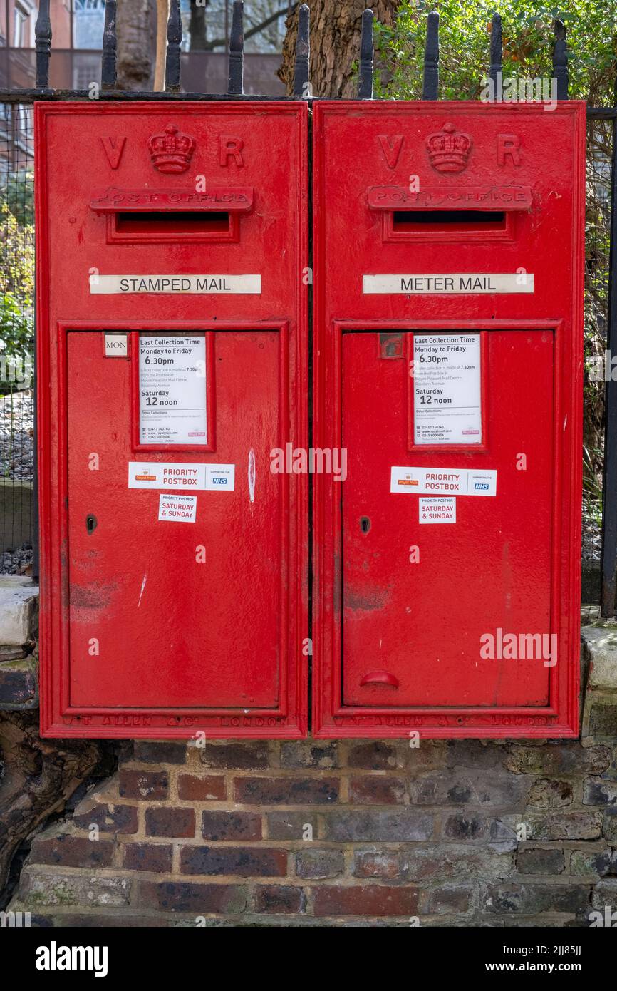 A pair of iconic red Victorian wall Royal Mail post office letter boxes affixed to railings in the City of London still in use today Stock Photo