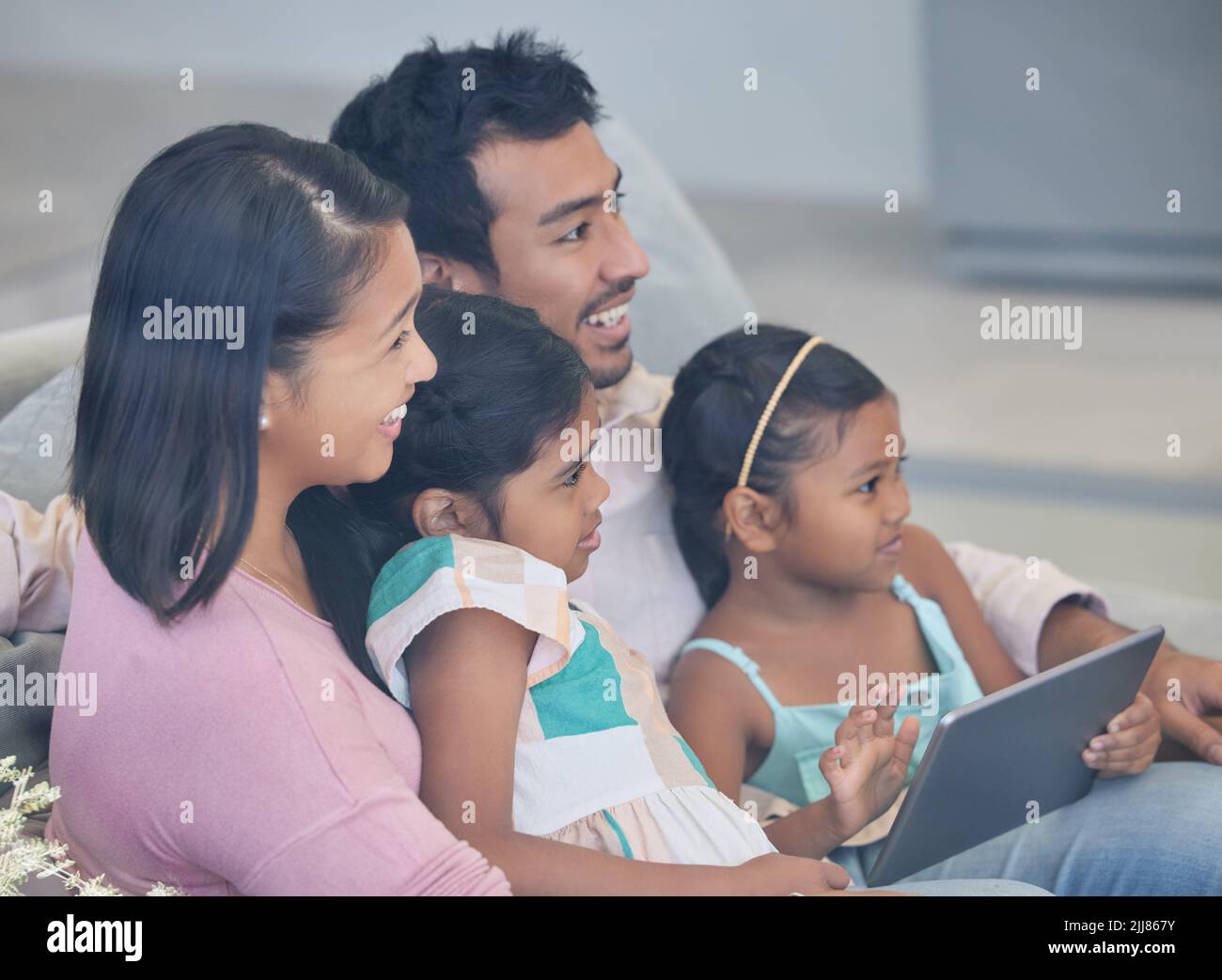 Teaching the little ones the way of the world. a young family relaxing together while using a digital tablet. Stock Photo