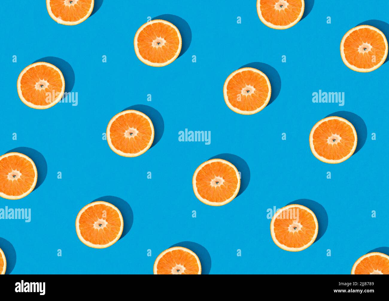 Top view orange fruit half cut pattern on sky blue background isolated. Fun creative fruit trendy abstract wallpaper design. Citrus fruit pattern crea Stock Photo