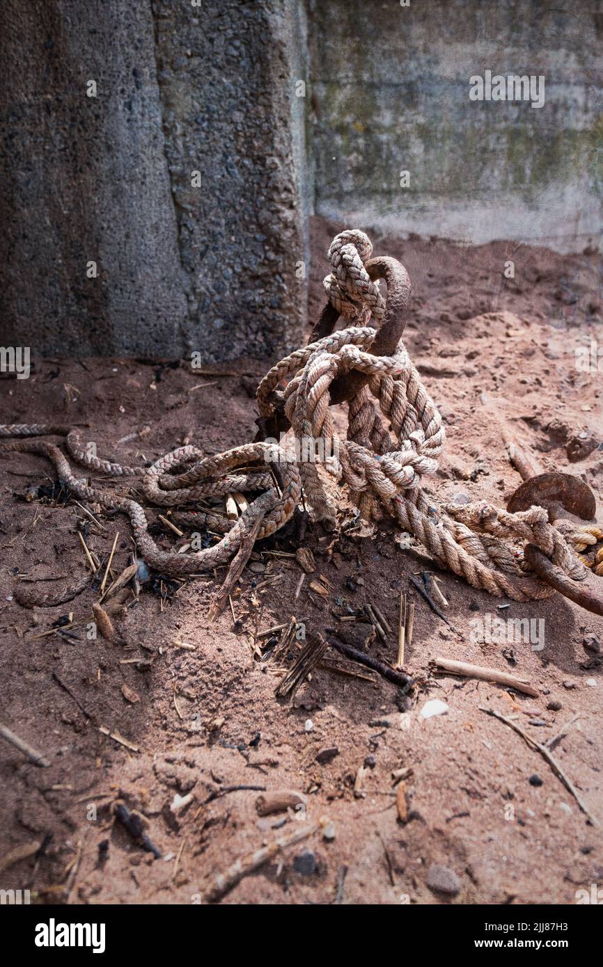 A vertical shot of an old rope around a boat mooring ring on the ground ...
