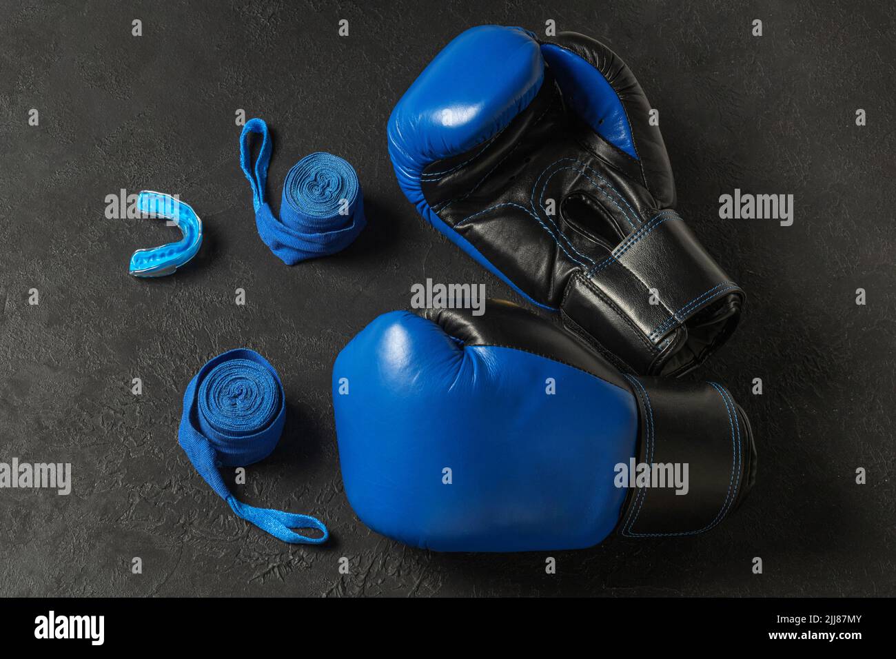 Blue boxing gloves with a cap and bandages on a black background. Stock Photo