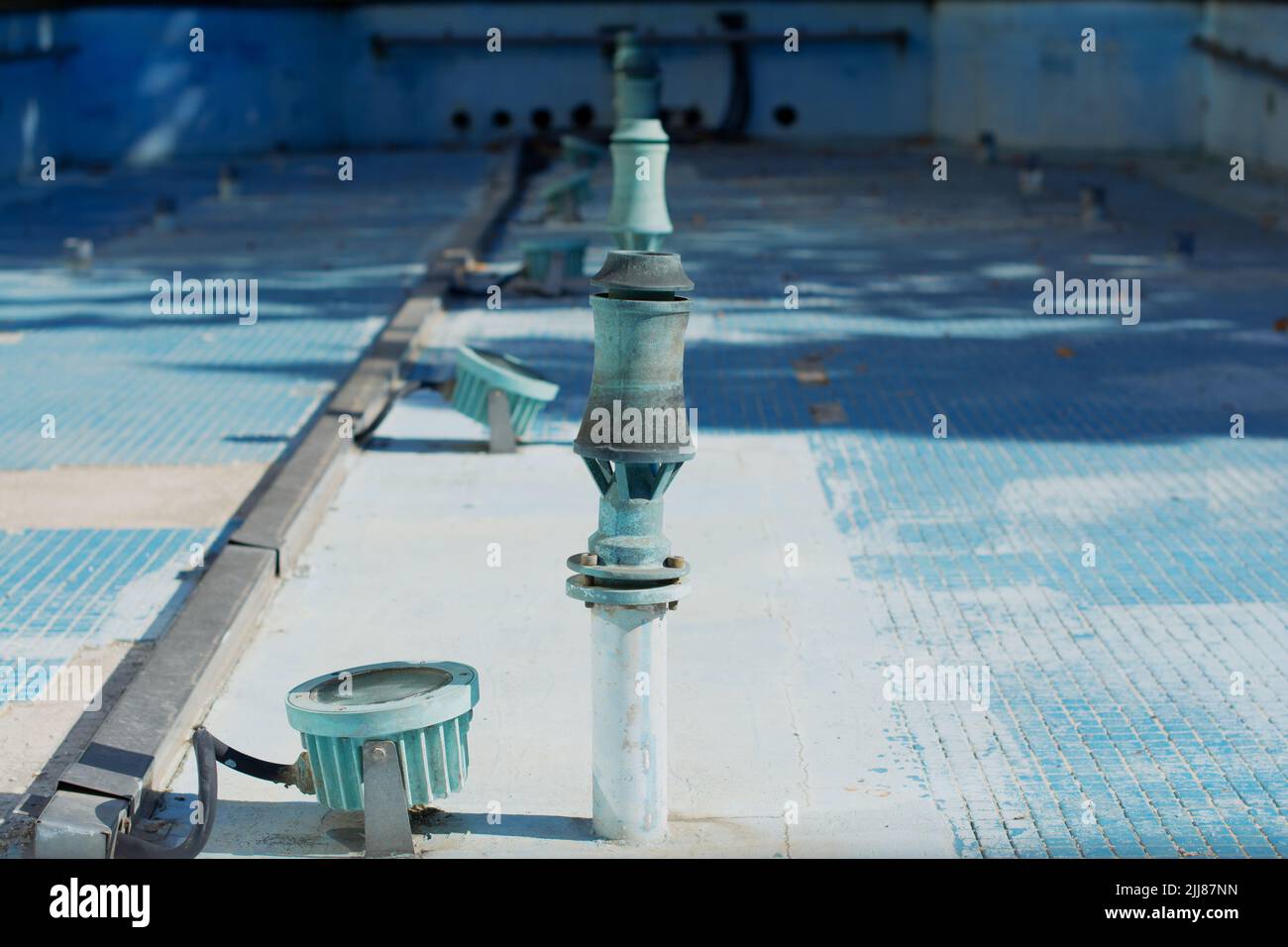 A fountain telescoping nozzle and an underwater spotlight in a fountain basin tiled with small blue tiles Stock Photo