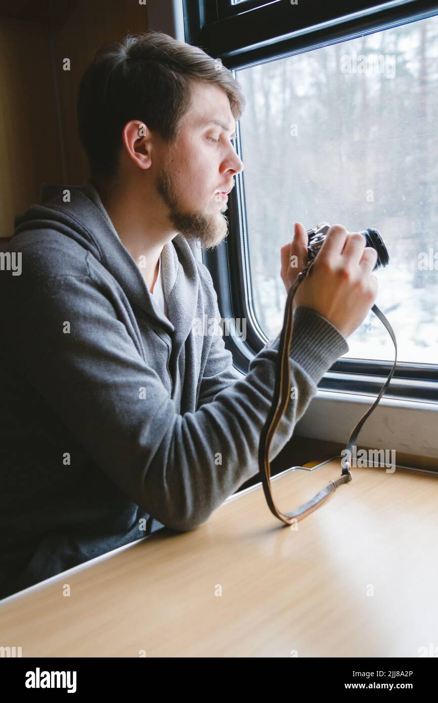 man sits at a table in a train with a camera Stock Photo