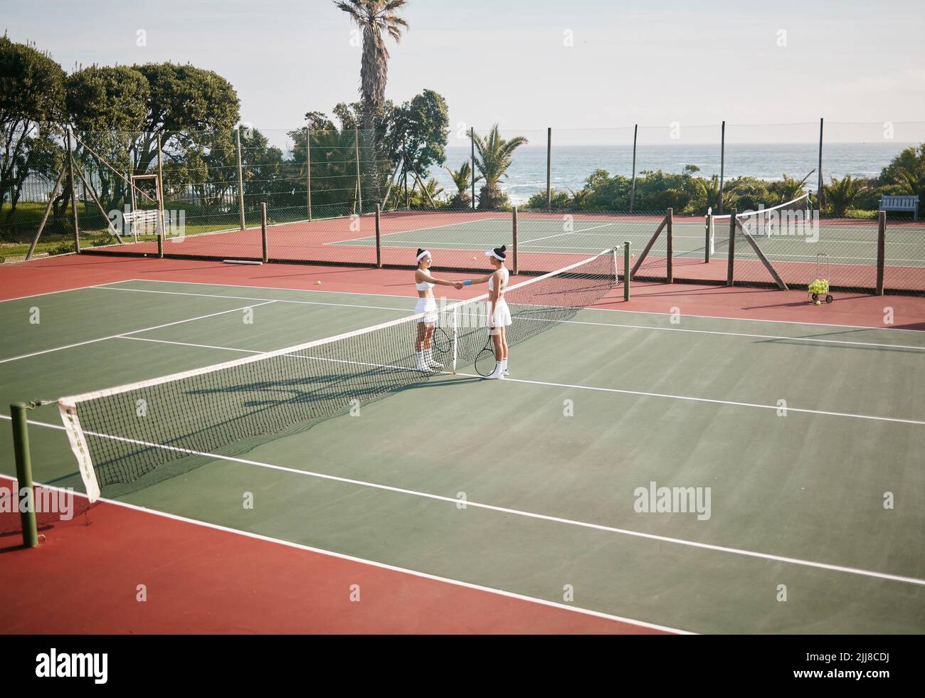 Good luck. Full length shot of two young tennis players standing together and shaking hands before practice. Stock Photo