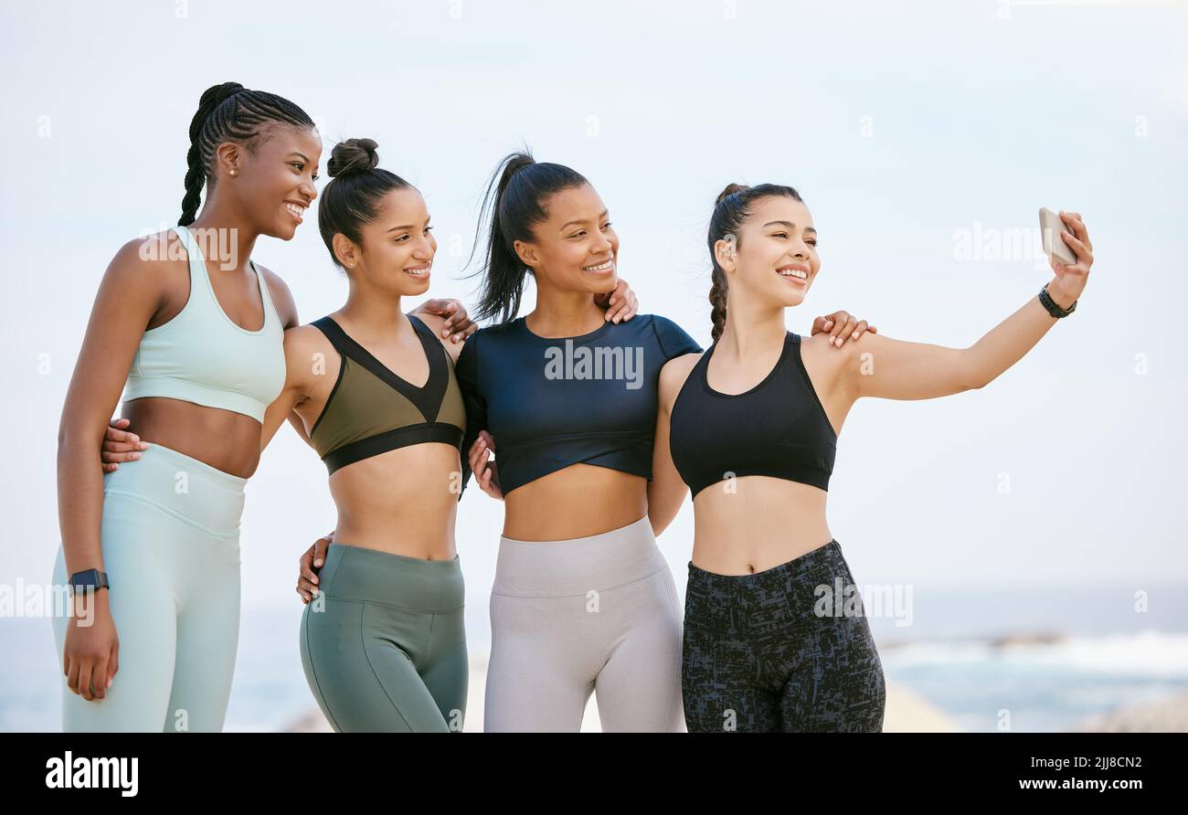 Ready to immortalize this moment. a group of friends taking selfies on the beach during a workout. Stock Photo