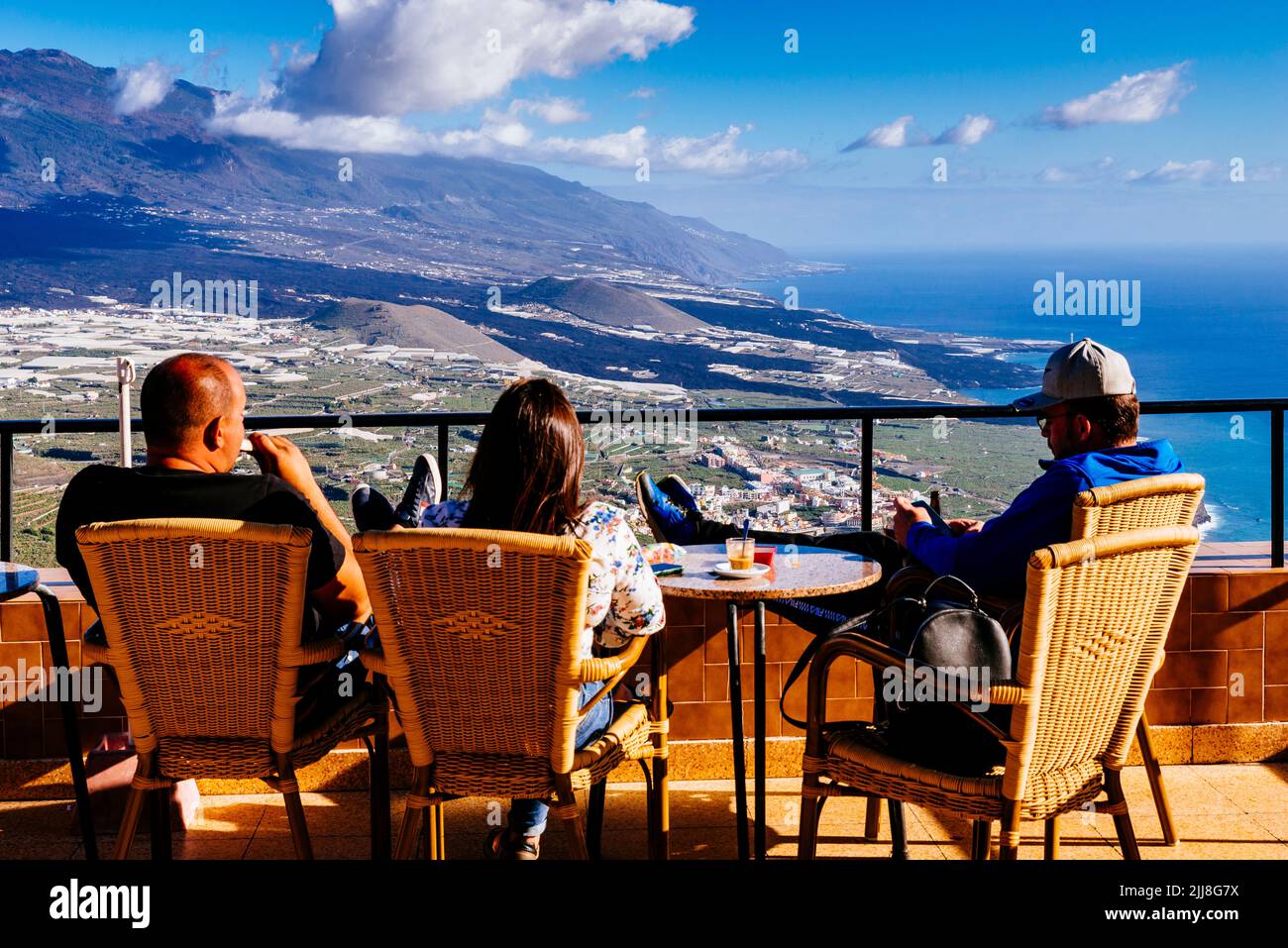 Tourists on a terrace look at the river of solidified lava that crosses the Aridane valley at sunset. La Palma, Canary Islands, Spain Stock Photo