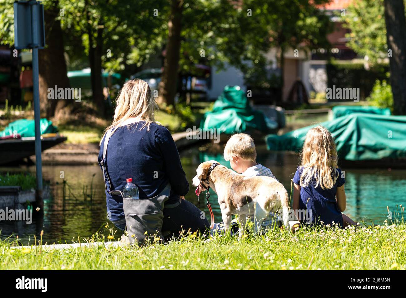 23 March 2022, Brandenburg, Lübbenau: A mother sits with her children and a dog at the harbor of the Spreewald town and enjoys the morning sun. Photo: Frank Hammerschmidt/dpa Stock Photo