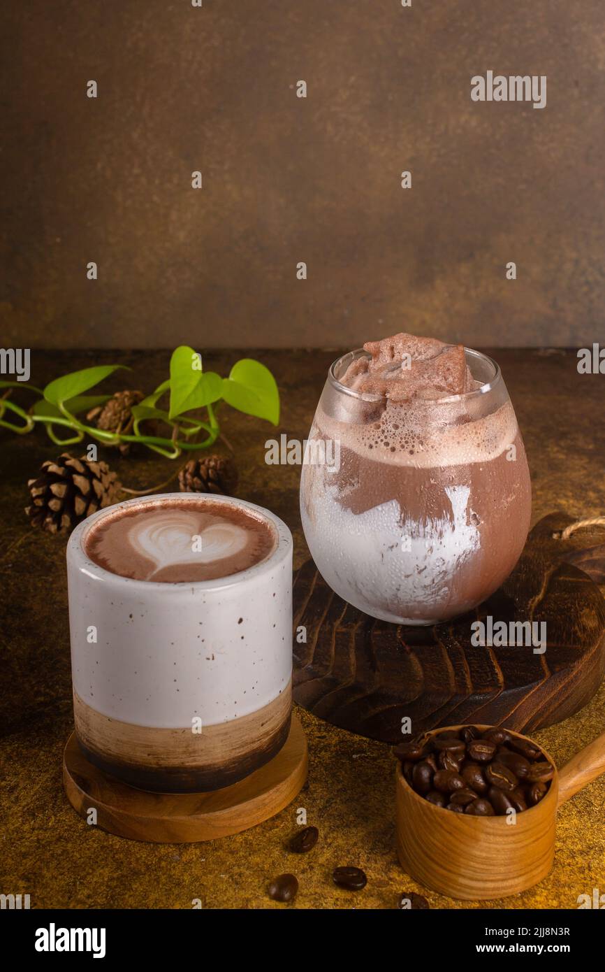 chocolate drink with ice in glass and hot in mug, on rustic wooden tray ...