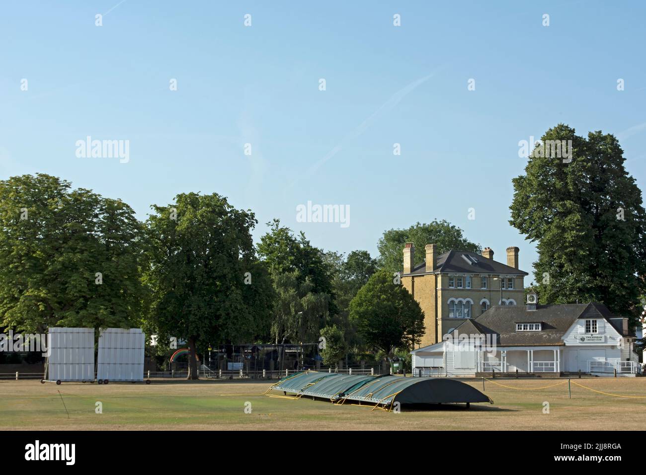 viewed across twickenham green, the covers, pavilion and a sight screen of twickenham cricket club, twickenham, middlesex, england Stock Photo