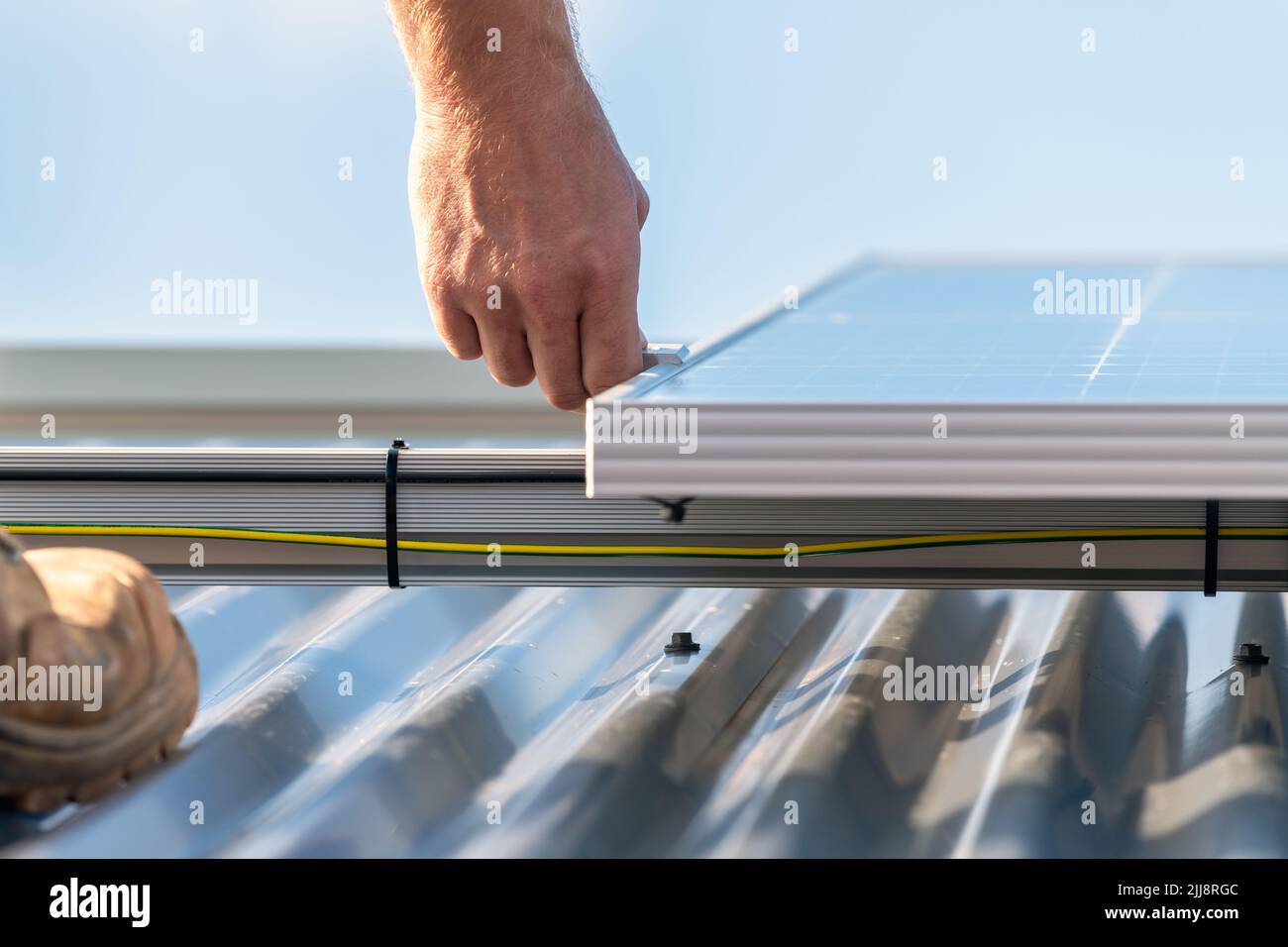 Solar panels installation to the house roof rack. Focus on hand Stock Photo