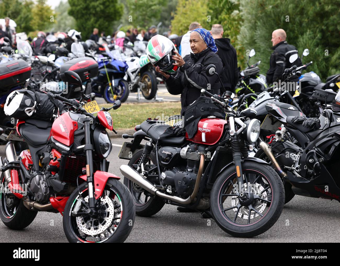 Hinckley, Leicestershire, UK. 24th July 2022. A rider puts on her crash helmet during a World Record attempt for the largest Female biker meet at the global headquarters for Triumph Motorcycles. Credit Darren Staples/Alamy Live News. Stock Photo