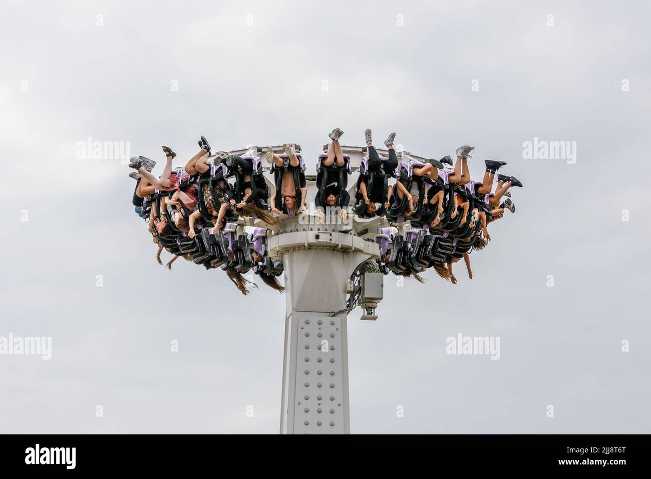 A pendulum ride gondola mid air with people hanging upside down with legs in the air. Stock Photo