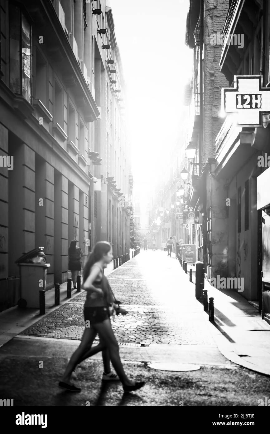 Madrid, Spain - September 6, 2016: Brightly lit by sunlight street with walking people in Madrid. Black and white photography Stock Photo