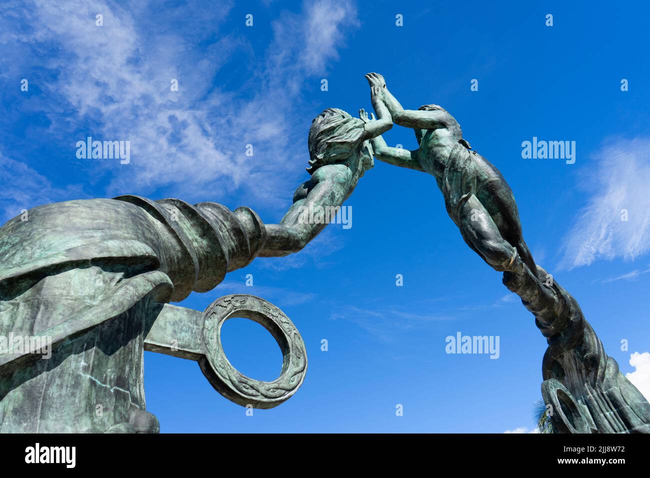 Bronze statue against the blue sky of the two lovers in Playa del Carmen, Mexico. Shot from below. Hand holding statues Stock Photo