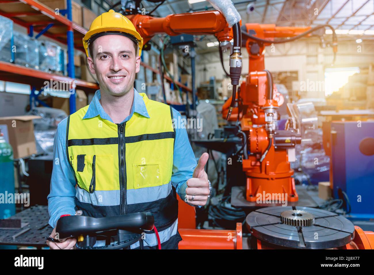 Portrait smart engineer man working with advance robotic machine weling in heavy industry. Stock Photo