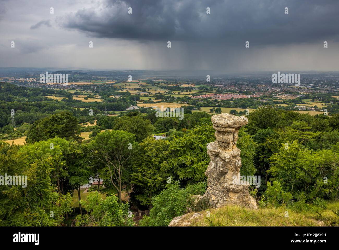 The Devil's Chimney on Leckhampton Hill with an approaching thunderstorm over Cheltenham Spa, Gloucestershire, England Stock Photo