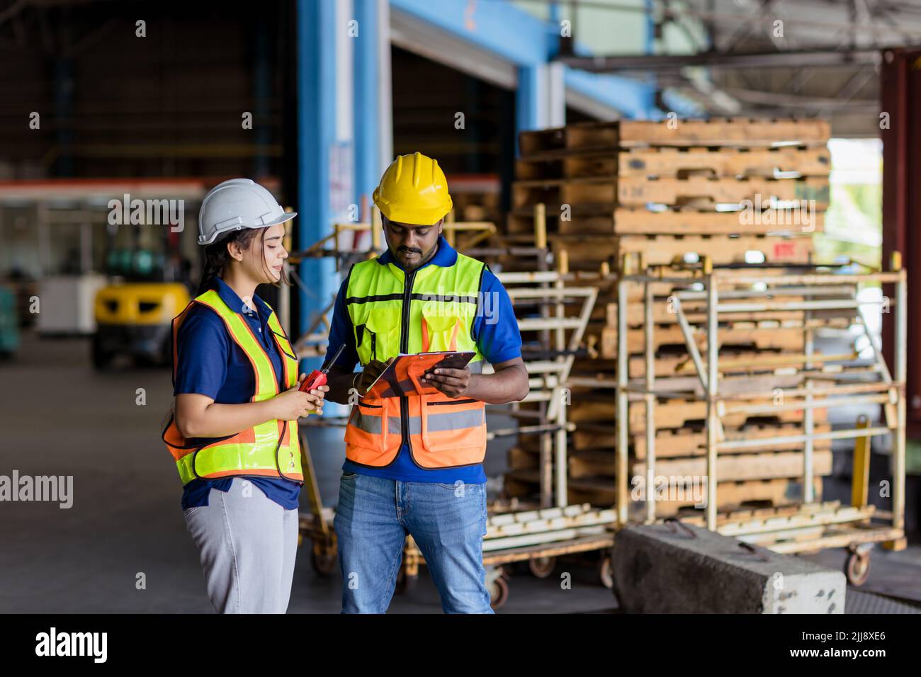 Hispanic Indian engineer worker working in port shipping cargo together. woman work with male in warehouse industry. Stock Photo