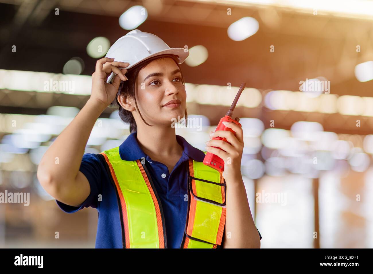Portrait Indian woman worker supervisor with engineer safety suit work in large factory warehouse Stock Photo