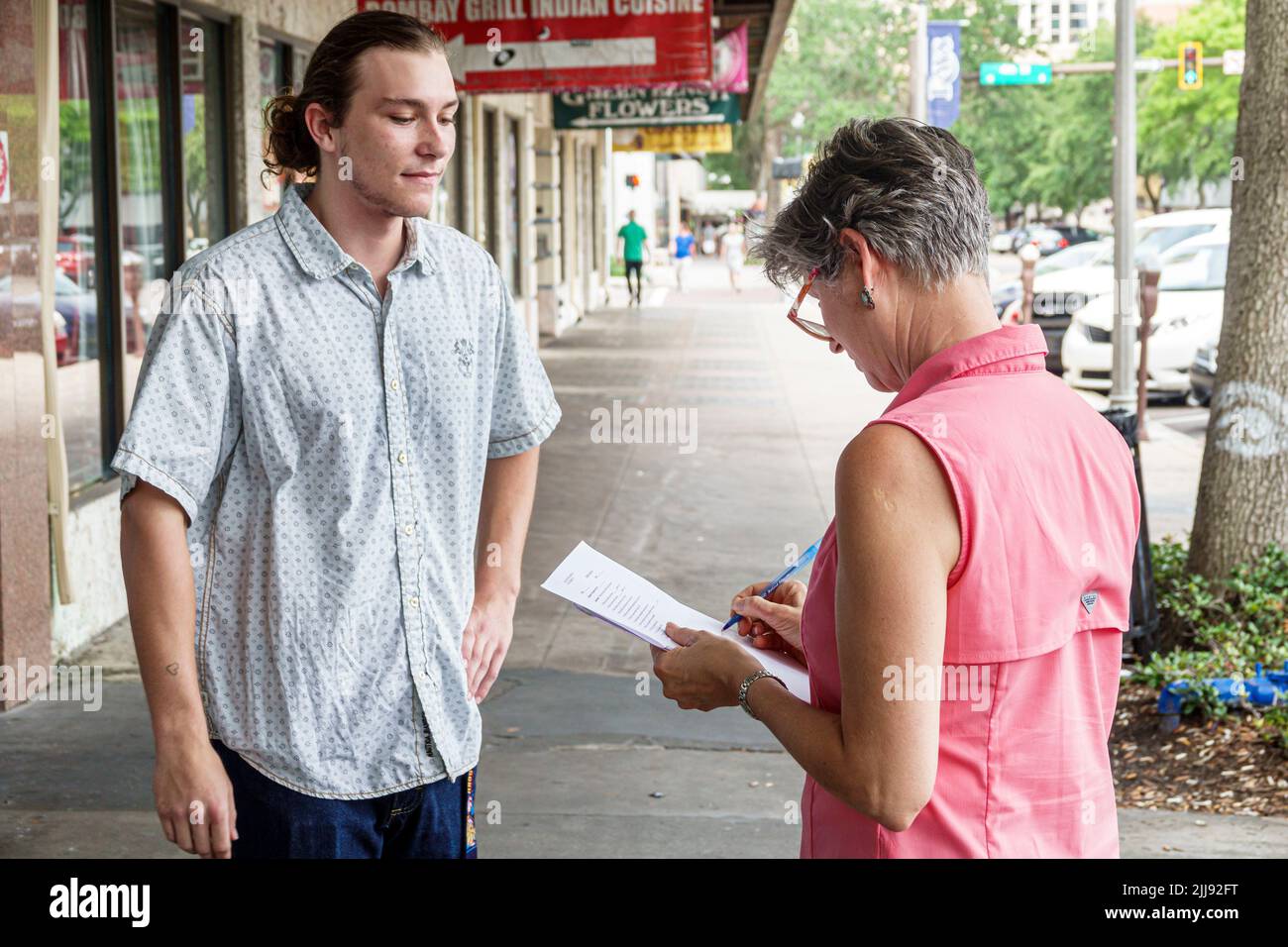 St. Saint Petersburg Florida,Central Avenue,survey petition questionnaire opinion poll,adults woman female man male,asking questions street sidewalk Stock Photo