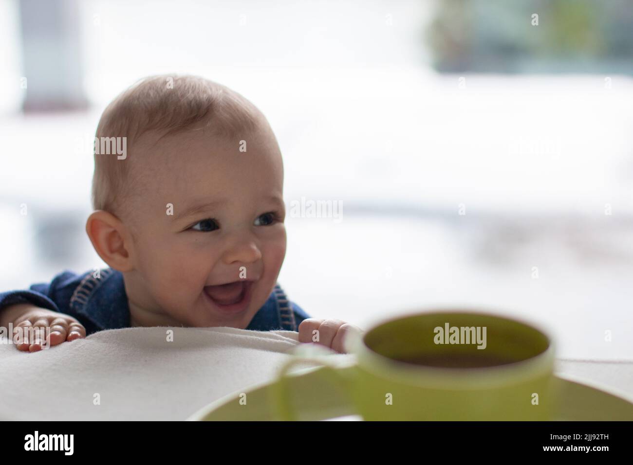 Laughing mischievous toddler with a cute naughty expression, little blonde boy troublemaker, daily home life childhood scene Stock Photo