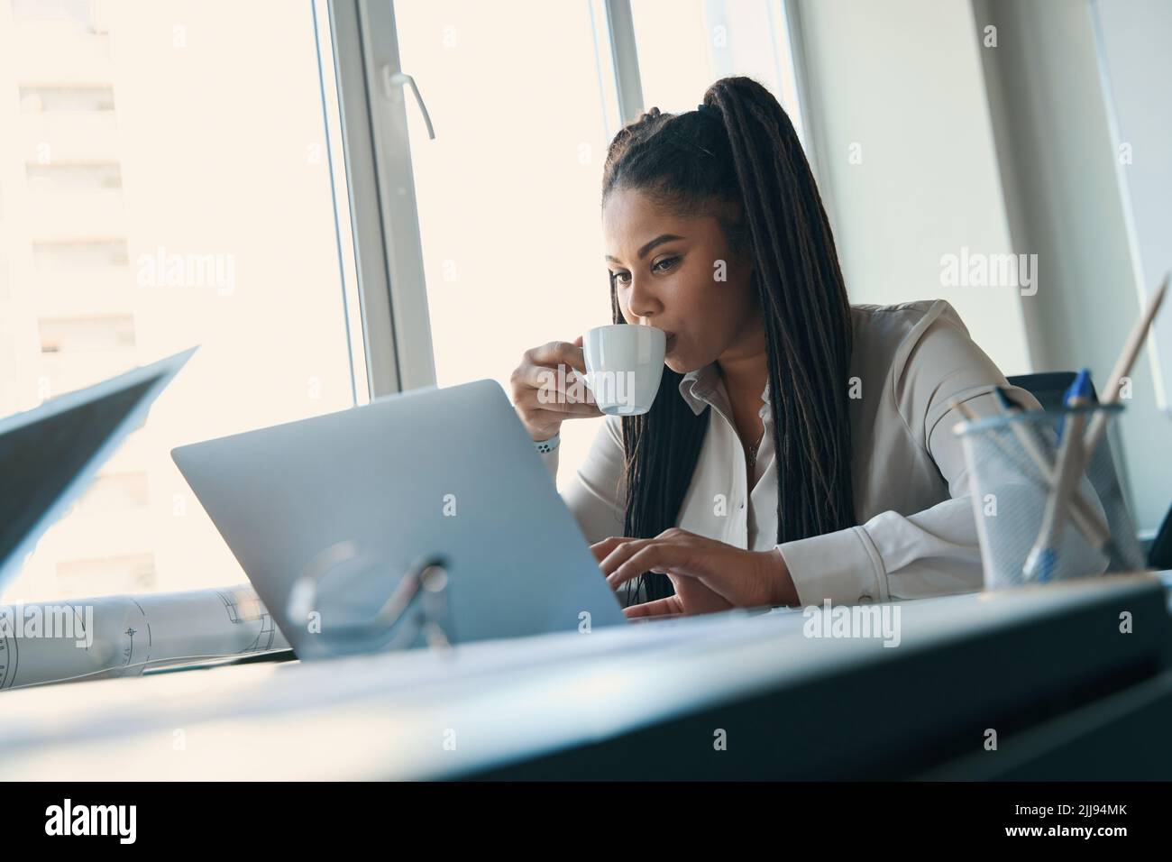 Focused draftswoman using computer during coffee break Stock Photo