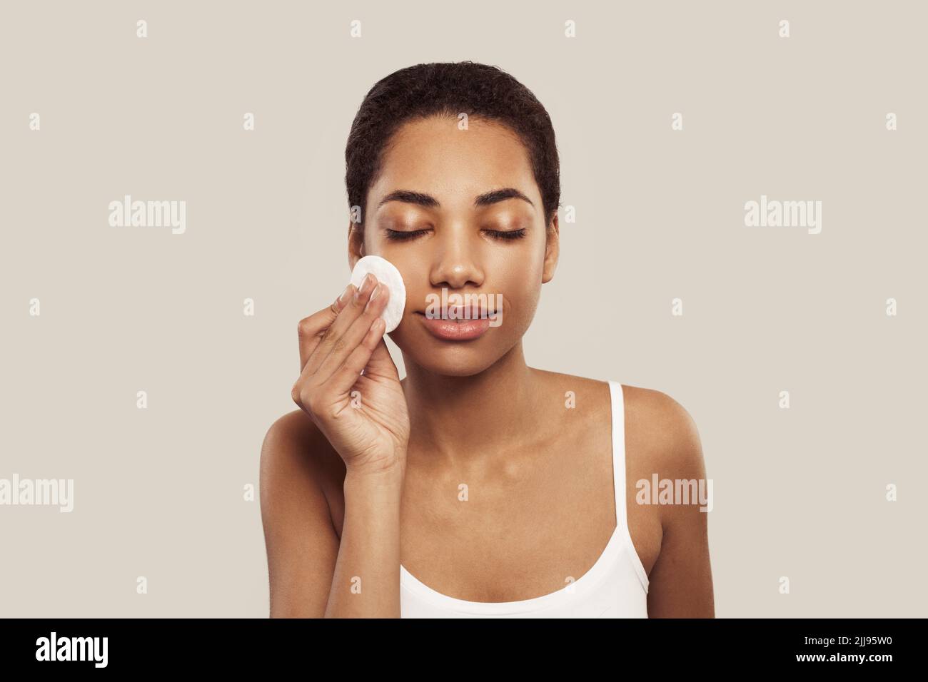 Black smiling woman remove make up with white cotton pad Stock Photo