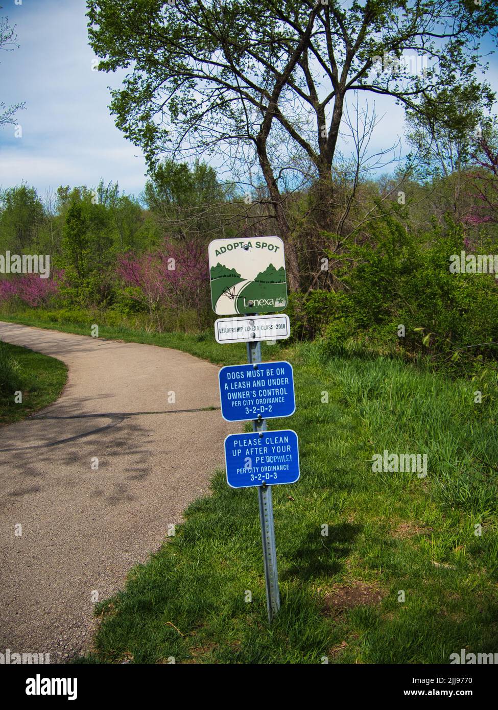 A "Please clean up after your pet" sign with graffiti on it at
