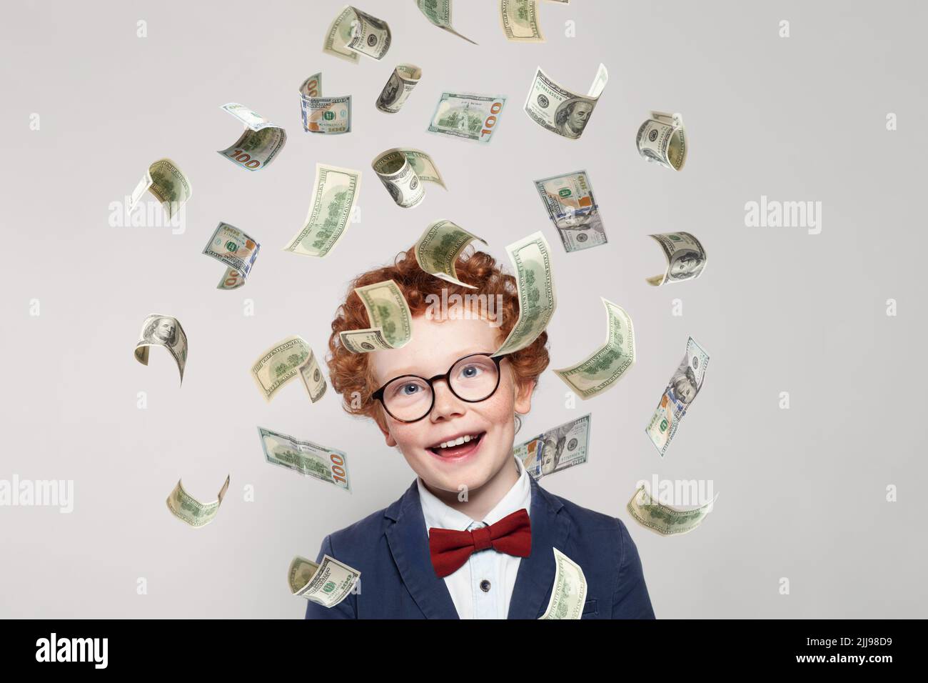Curious redhead little kid boy with us dollar money rain on white background Stock Photo