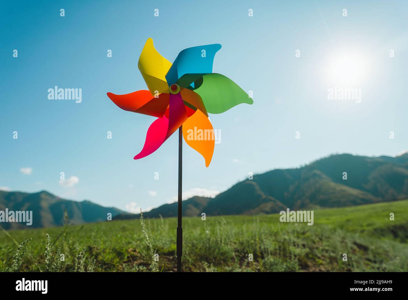 Windmill against, pinwheel the backdrop of green mountains and sky Stock Photo
