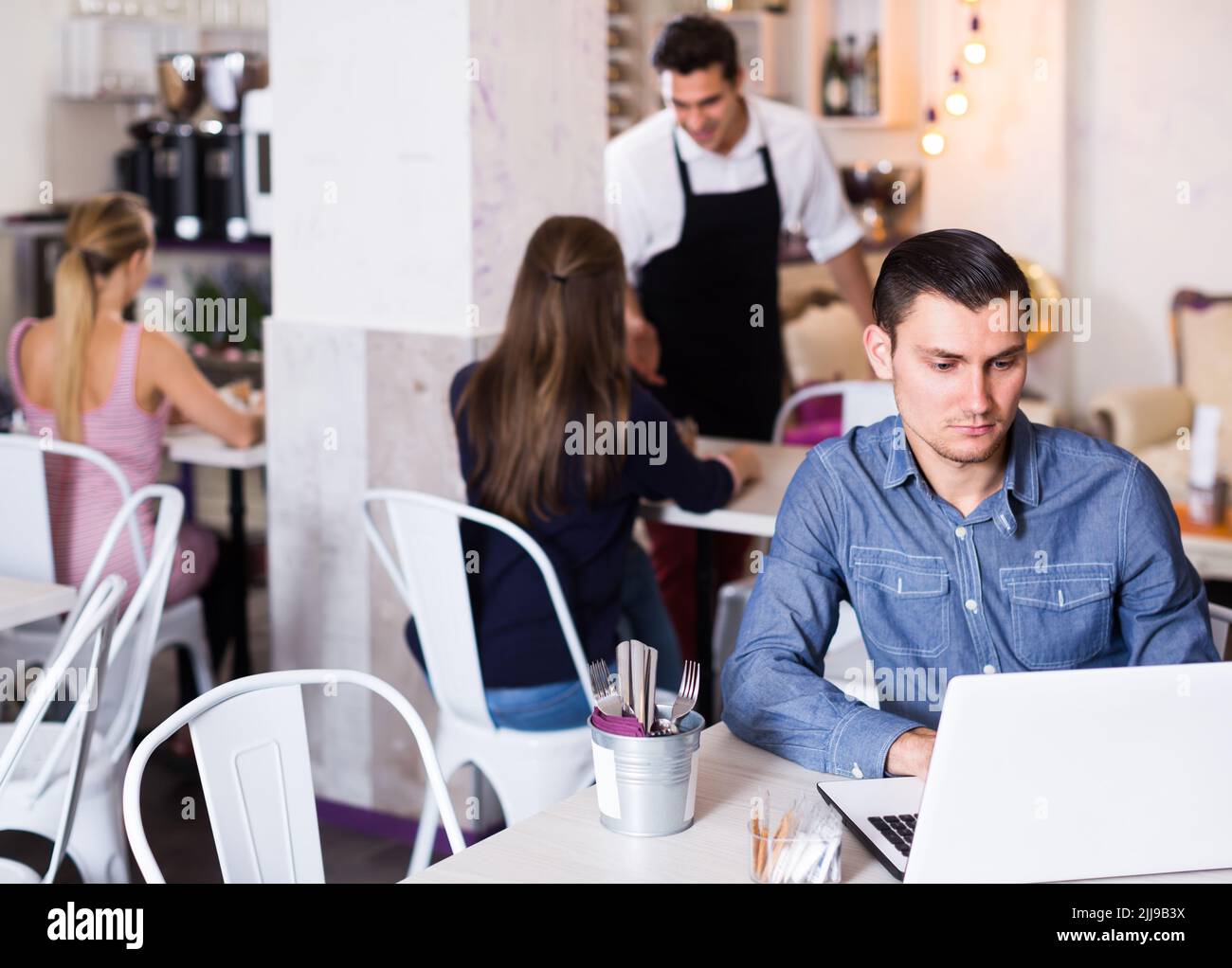 concentrated young man using laptop in modern cafe Stock Photo