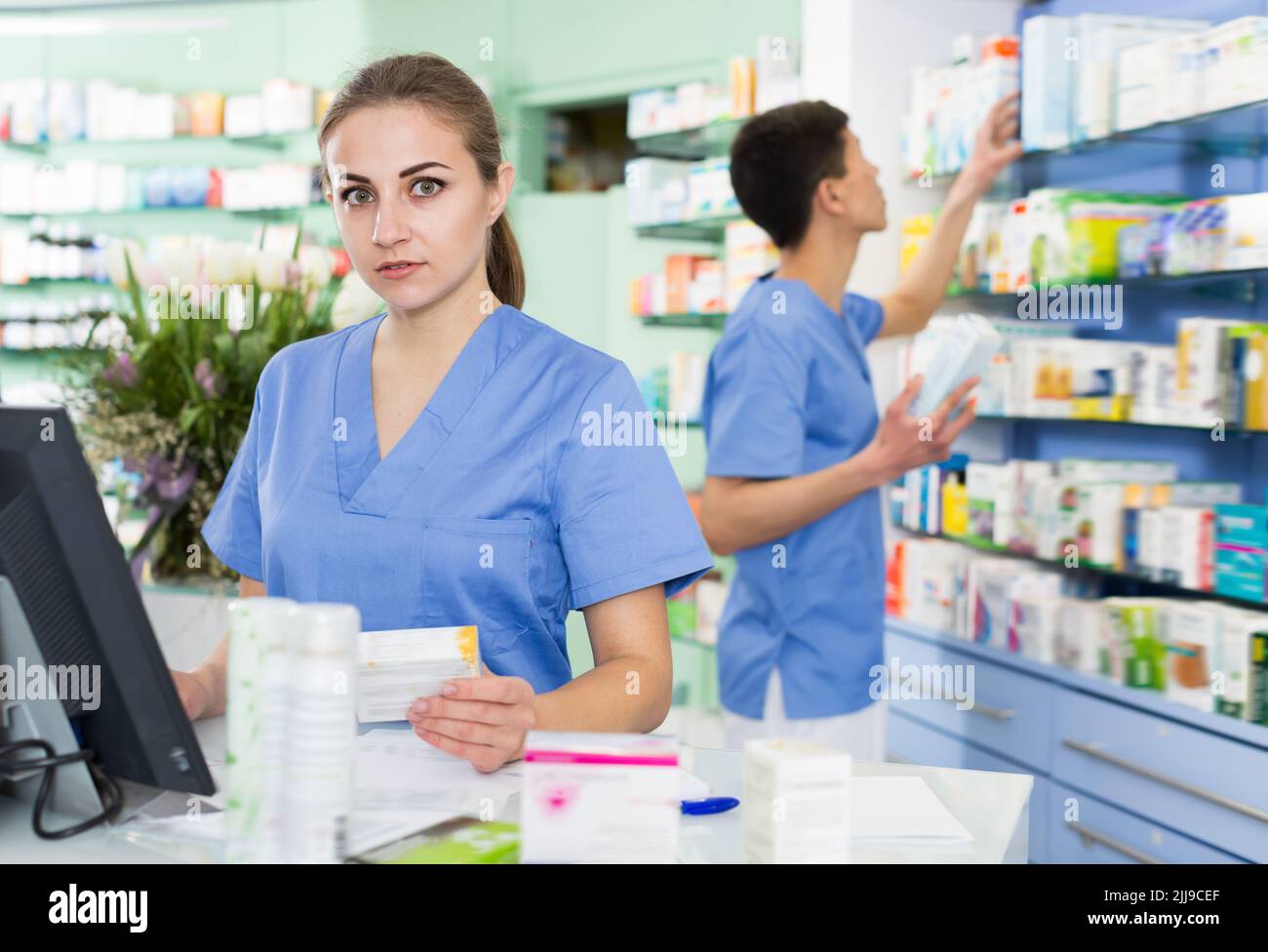 Adult pharmacist is standing near cashbox Stock Photo