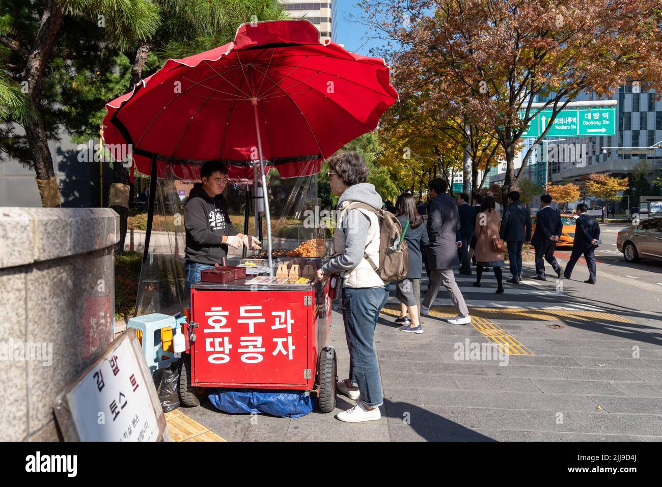 Seoul, South Korea - November 04, 2019: Woman buying food at food stall at the street at Yeouido district. It is a Seoul's main finance and investment Stock Photo
