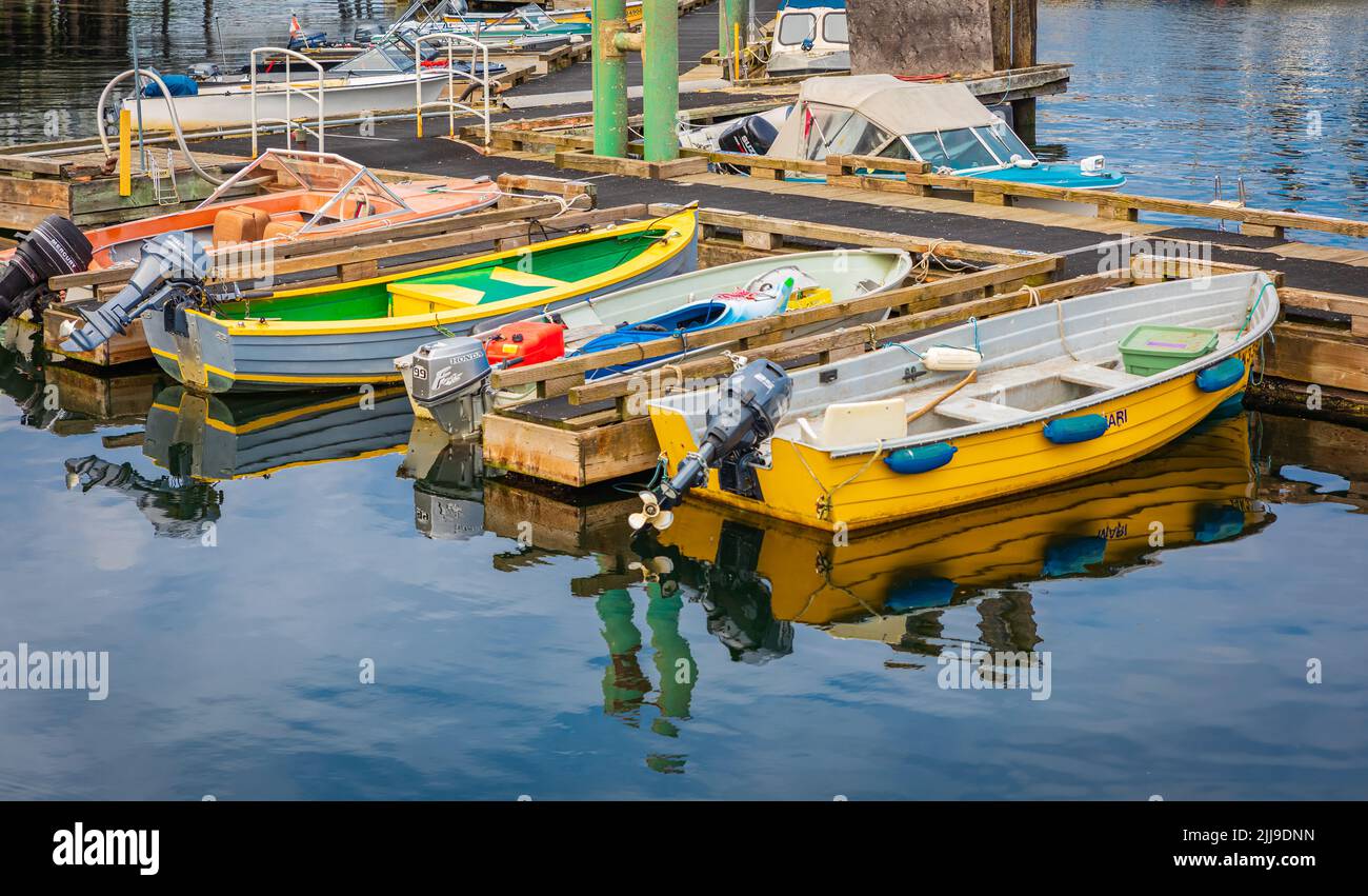 Colorful small boats parked to wooden pier with reflection in a water. Motor boats in marina on a summer day. Nobody, travel photo-Nanaimo BC Canada-J Stock Photo