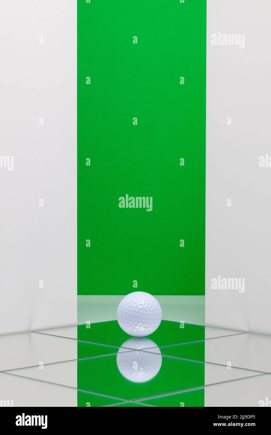 White golf ball on the floor from mirrors. White golf ball on green  background.  Sport Concept and Idea Stock Photo