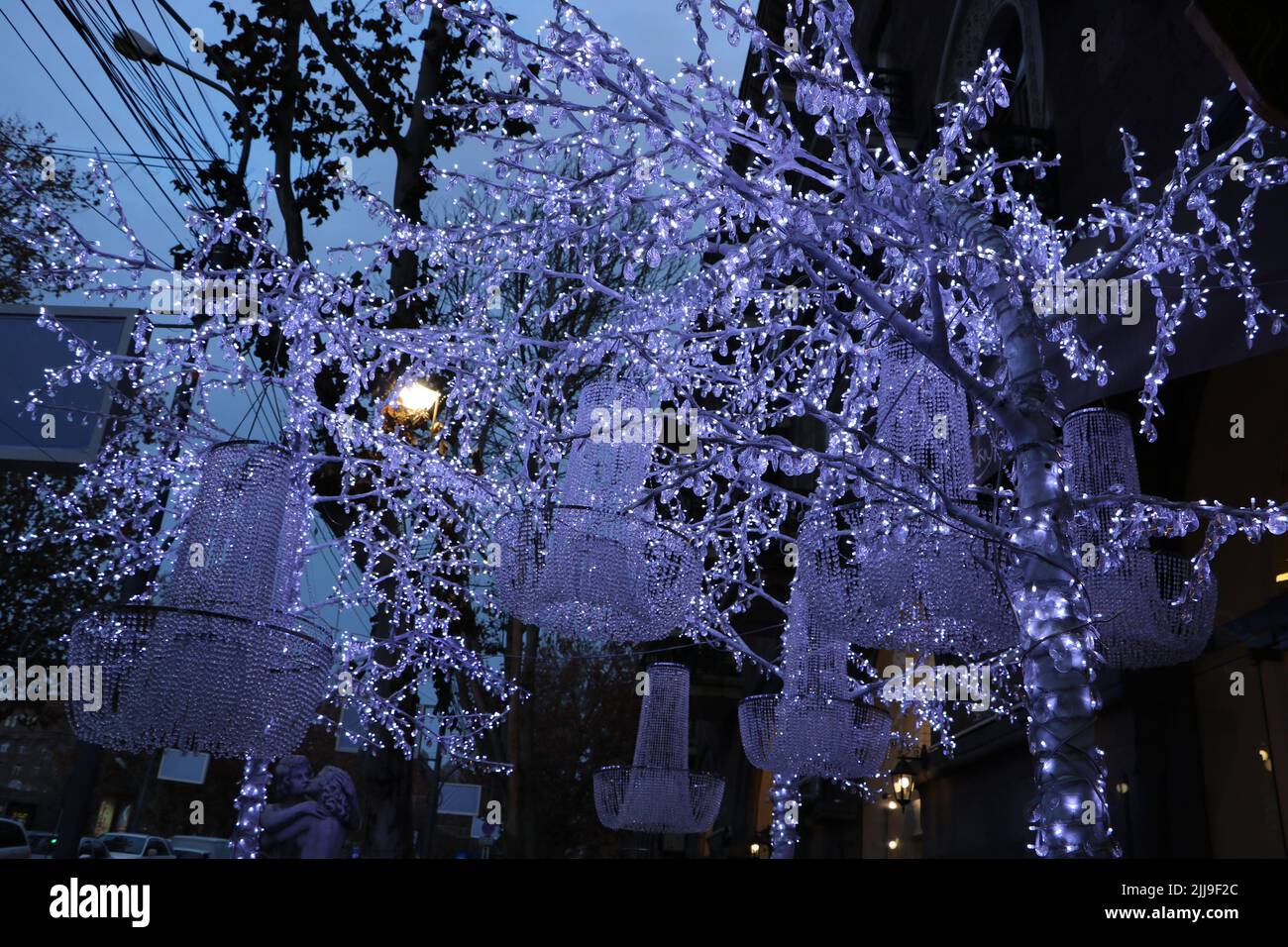 A street decorated with white garlands and chandeliers hanging on the ...