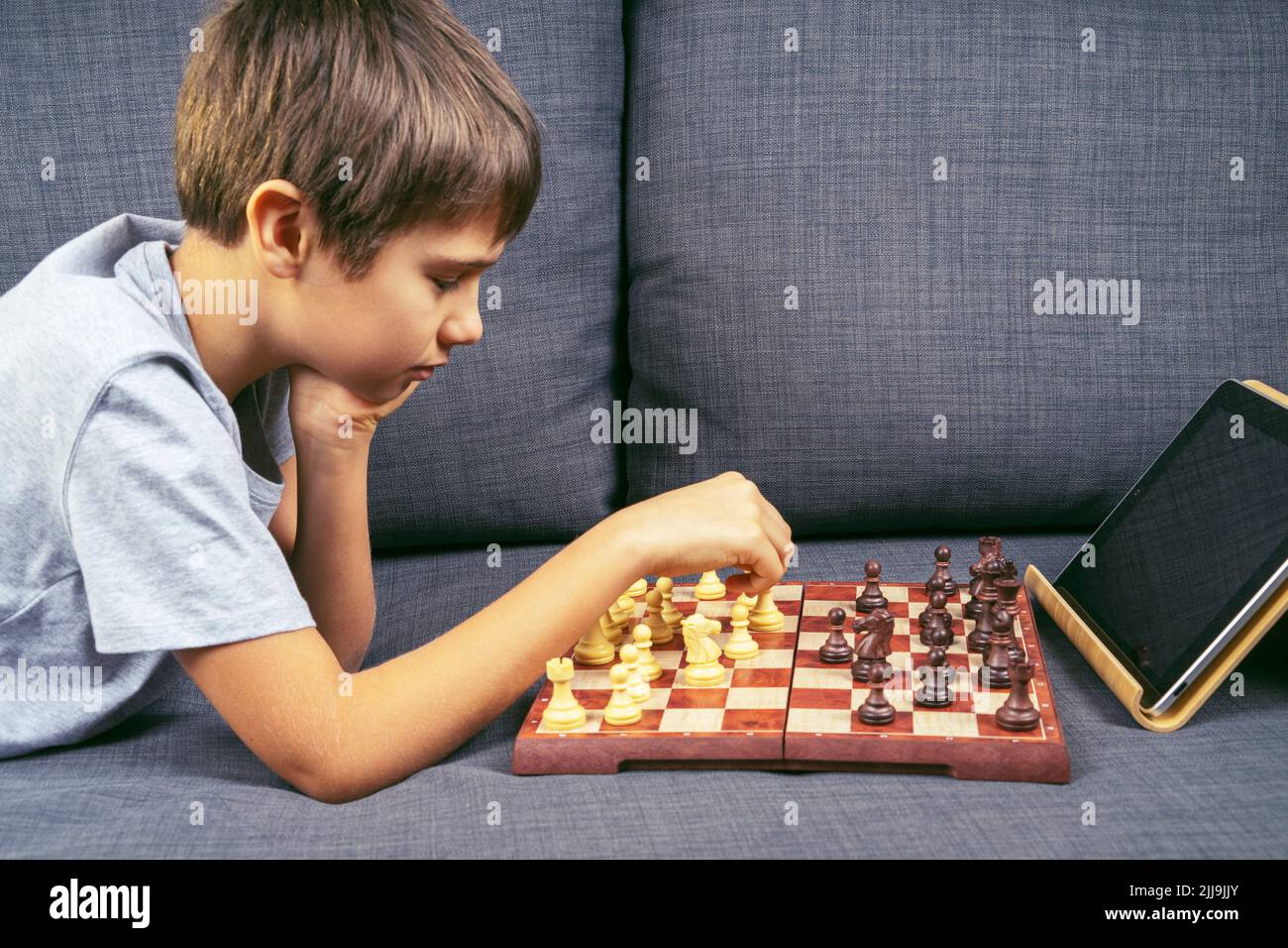 Teenage boy learning to play chess online with tablet computer