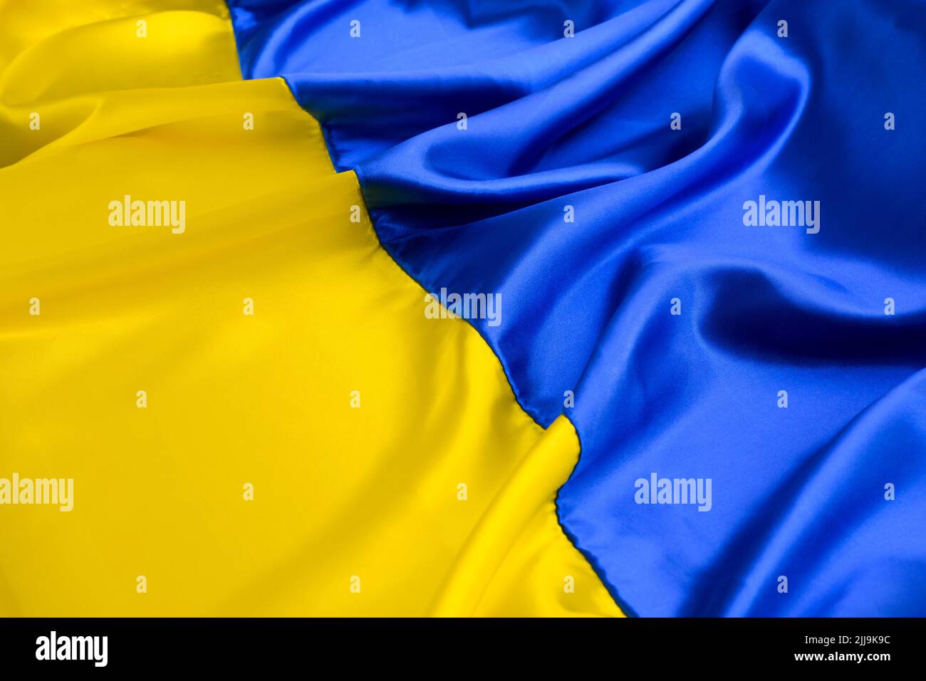 Fabric wave flag of Ukraine, UA. Blue and yellow bright colors. Close up curved texture background Stock Photo