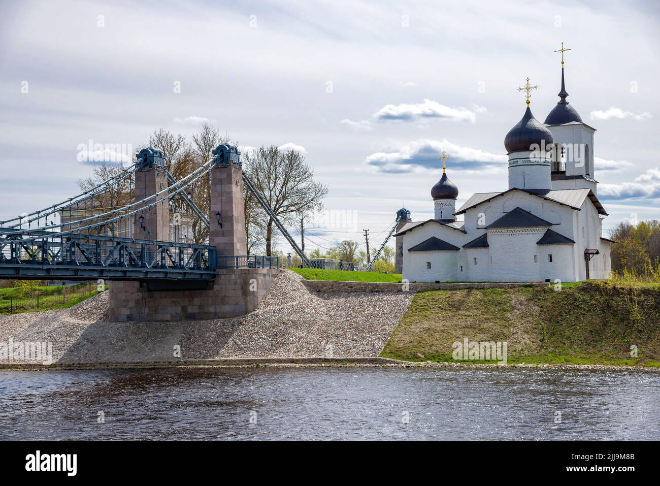 View of the chain bridge and the Church of St. Nicholas the Wonderworker, the city of Ostrov. Pskov region, Russia Stock Photo