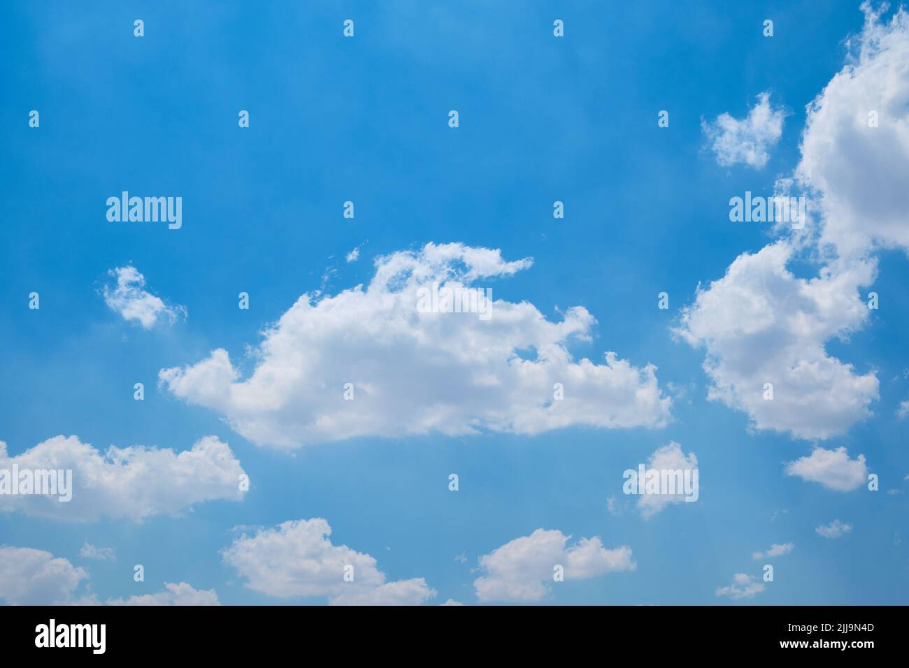Cumulus clouds against bright blue sky Stock Photo