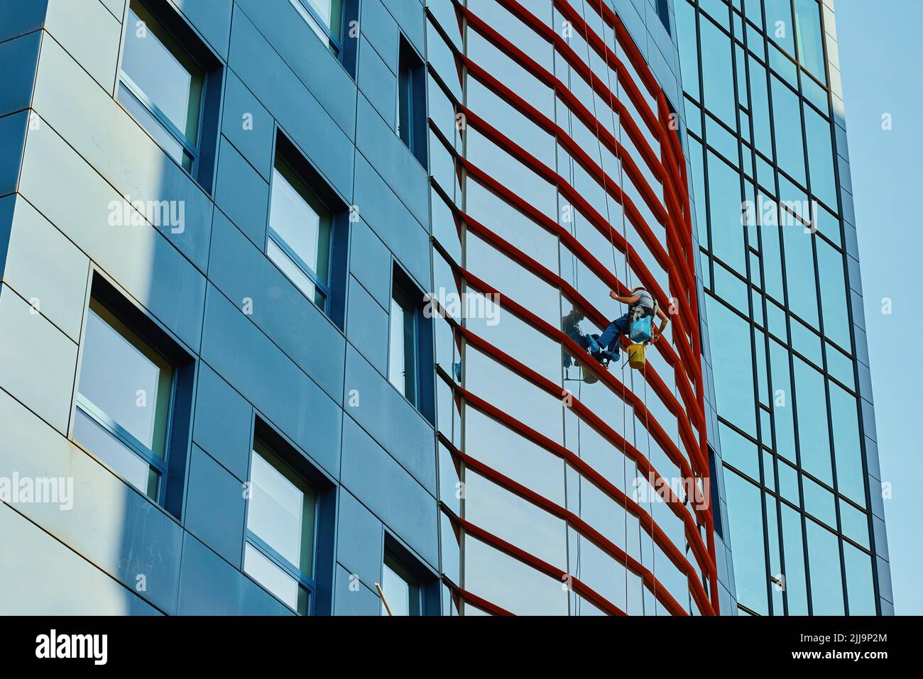 Two workers cleaning window in business center, Industrial alpinists washing exterior of skyscraper, Dangerous risky work at height, Cleaning service Stock Photo