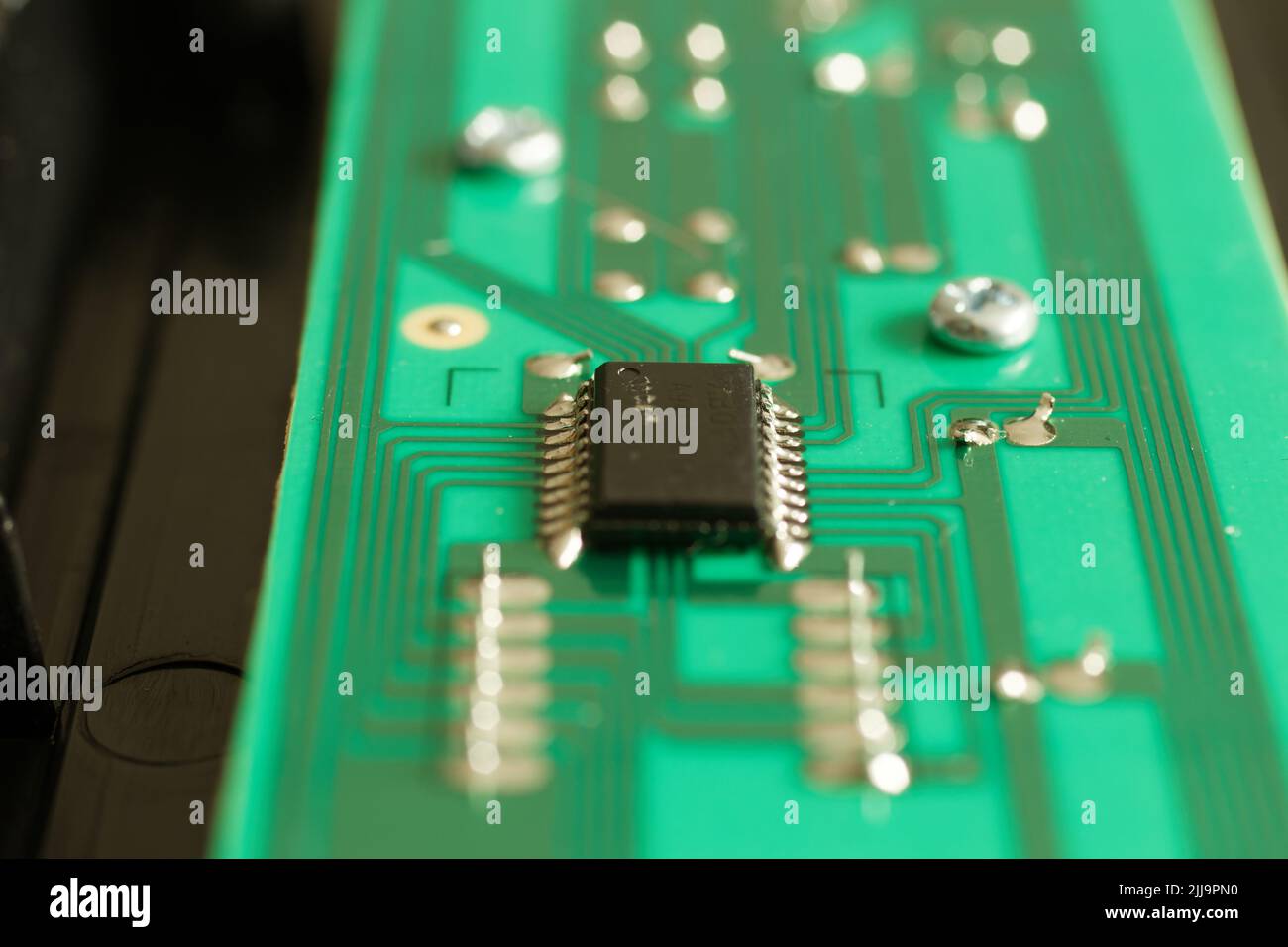 Close up of an electronic component on a green circuit board with deep bokeh Stock Photo