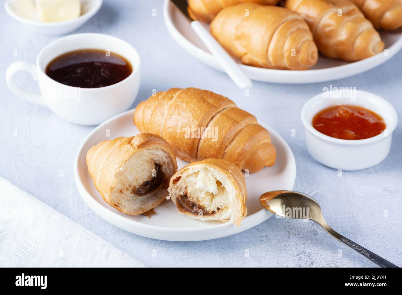 A freshly baked French Croissant, coffee, butter and jam Stock Photo